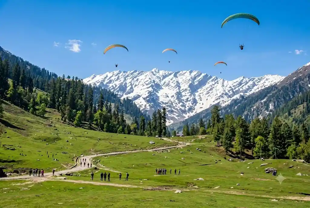 Paraglider flying over Solang Valley near Manali with snowy mountains in the background